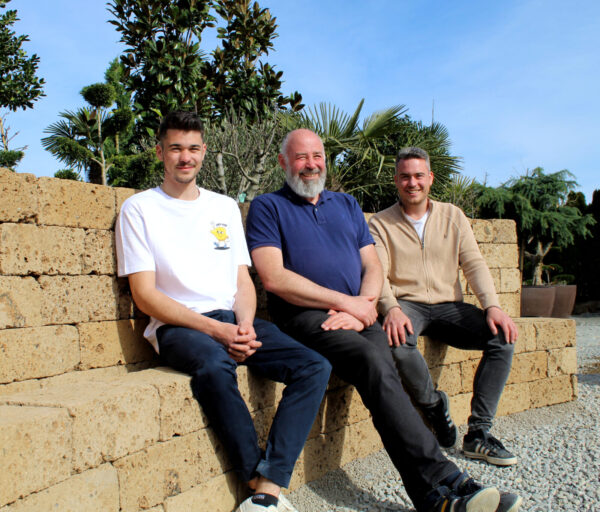Vater und seine Söhne sitzen auf einer Steinmauer.