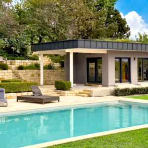 Zeigt eine attraktive Garten-Pool-Anlage mit Natursteinmauern und Natursteinterrasse, Poolhaus und Naturpool.