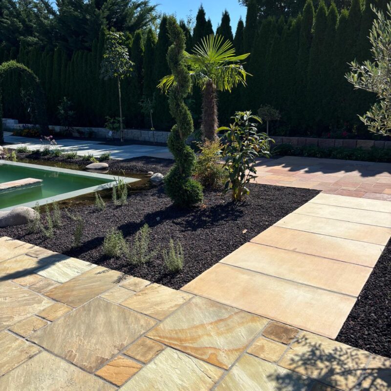 Zeigt verschiedene Sandstein Natursteinbeläge mit mediterraner Bepflanzung